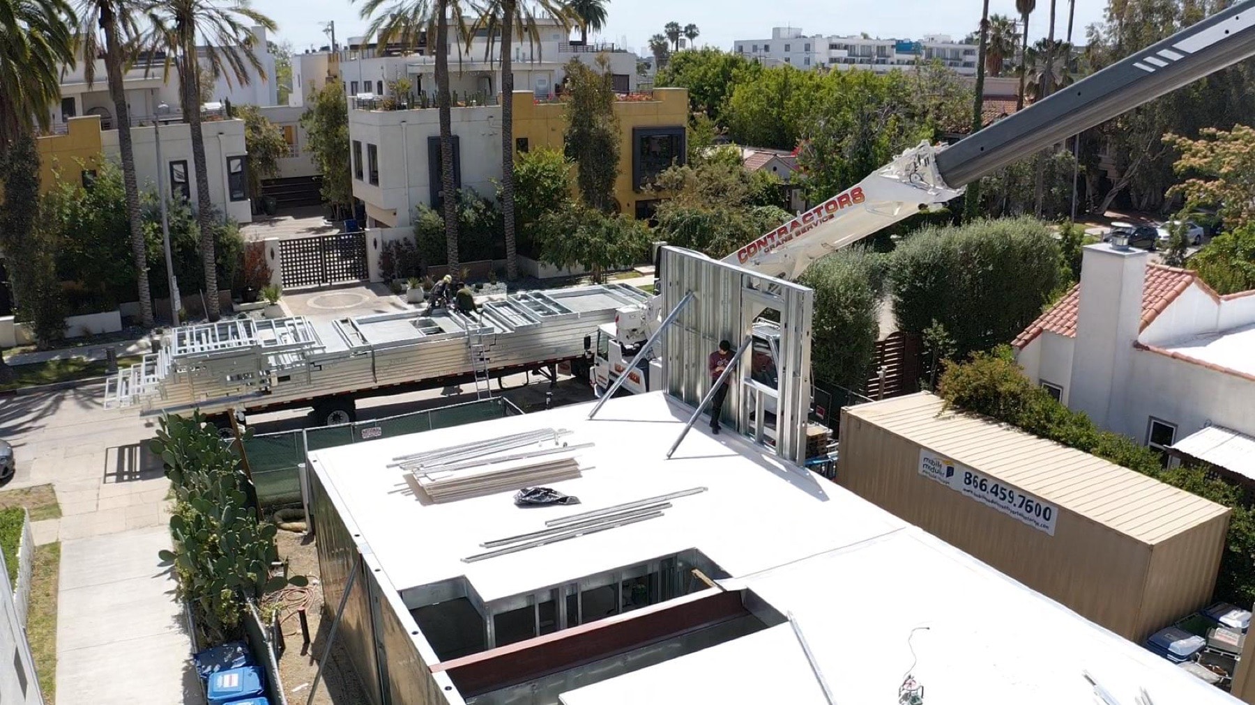 Aerial of a crane lifting panelized light gauge steel wall sections onto the 823 North June Street multifamily infill structure.