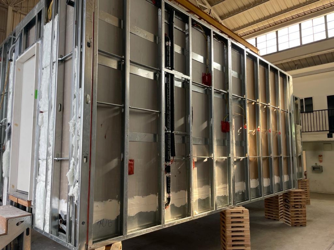 Steel-framed volumetric housing modules lined up on the factory floor.