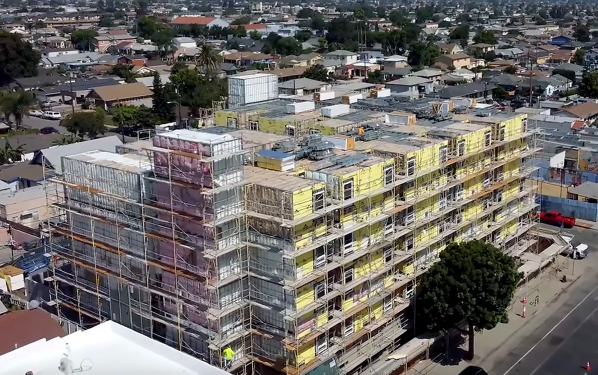 Aerial view of a multi-story modular light gauge steel residential building under construction in a Southern California neighborhood